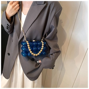 Detail of transparent sapphire blue acrylic mini bag with gold chain and bead handle