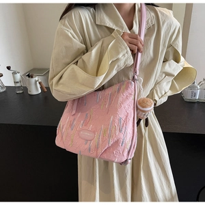 Detail showing pink bag with embossed texture, colorful embroidery, and a plush charm