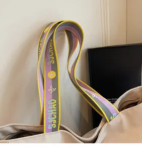 Detail of canvas tote bag featuring an ethnic purple and yellow jacquard webbing strap