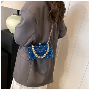 Detailed view of a navy blue bubble textured chain bag worn with a grey blazer