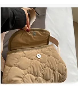 Detail view of the silver magnetic closure and wave quilting on a khaki crossbody bag