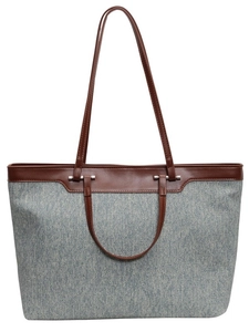 Front view of large gray-blue denim tote bag with brown leather handles and silver hardware
