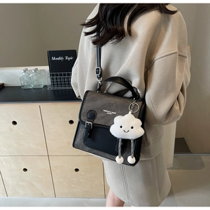 Detalle de bolso bandolera retro gris y negro con un colgante de nube blanca