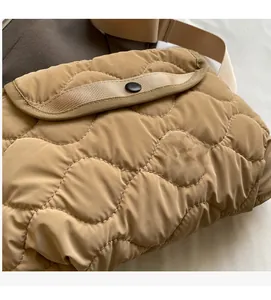 Detailed close-up of khaki quilted crossbody bag featuring wave stitching and black snap button