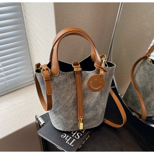 Detailed close-up of grey denim bucket bag with brown leather straps and gold lock