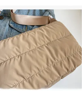 Détail de la texture du sac matelassé beige posé sur une veste en jean bleue