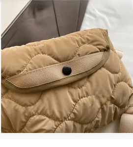 Detail of khaki quilted puffer shoulder bag with button closure and soft fabric texture