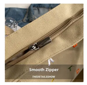 Nahaufnahme des glatten Reißverschlusses und der farbigen Buchstabenstickerei auf dem Canvas-Shopper