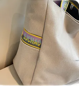 Detail of beige canvas tote bag showing thick texture and purple jacquard woven strap