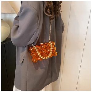 Detail of orange bubble texture mini bag with fine gold chain strap on grey blazer