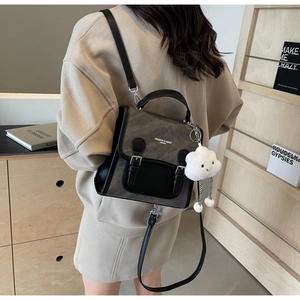 Detalle de mochila bicolor gris y negra con colgante de nube blanca y texto de moda