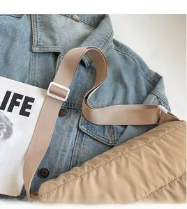 Vue détaillée de la large bandoulière en nylon et du tissu matelassé beige de ce sac bandoulière