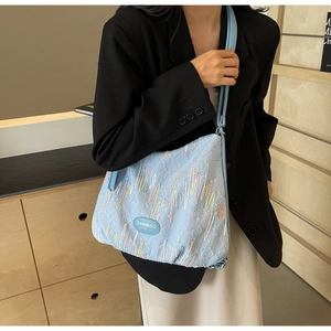 Detail of light blue pleated shoulder bag with colorful wave embroidery and brand logo