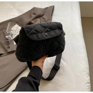 Detail of black puffer bag featuring classic quilted pattern and secure snap closure