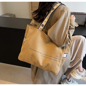 Detail of khaki canvas tote with poetic text and tricolor jacquard strap detail