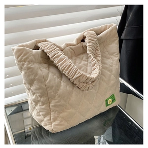 Close-up of beige quilted corduroy tote bag with diamond stitching and ruched handle