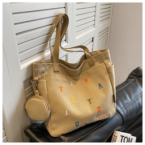 Detail of beige canvas tote bag with colorful letter embroidery and mini coin purse