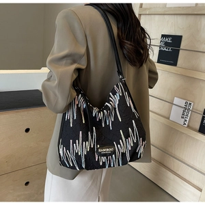 Close-up of black tote bag with wave embroidery and HAMIROO logo on a khaki blazer