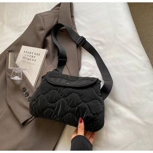 Detail of black quilted puffer bag showing plush cloud texture and wide adjustable strap