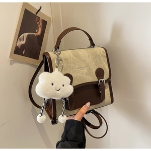 Detalle de bolso cuadrado vintage beige con ribete de cuero marrón y adorno nube
