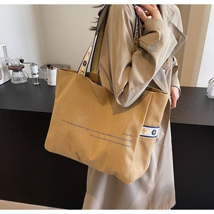 Detail of khaki canvas tote with inspirational text and ethnic embroidered strap