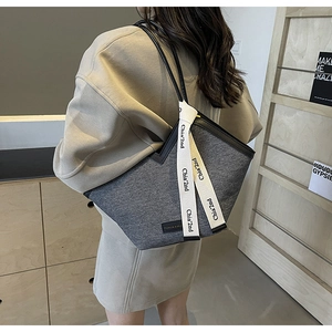 Détail du sac cabas en feutre gris avec garniture en cuir noir et ruban décoratif