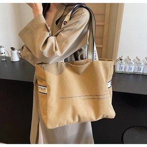 Close-up of khaki canvas tote bag with colorful striped straps and printed English text