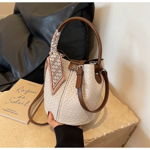 Close-up of bucket bag woven texture with silk scarf on handle and leather detail