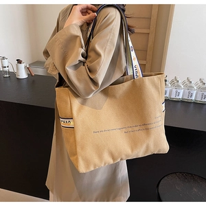 Detail of khaki canvas tote bag with woven blue and white shoulder strap showing the texture