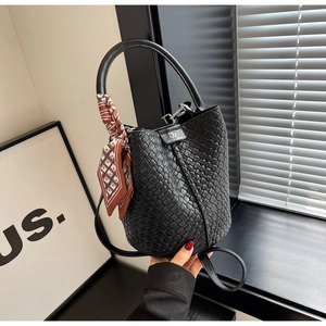 Detail of black woven bucket bag with patterned silk scarf and round top handle