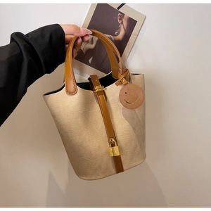 Detailed shot of canvas bucket bag with brown leather handles and golden padlock