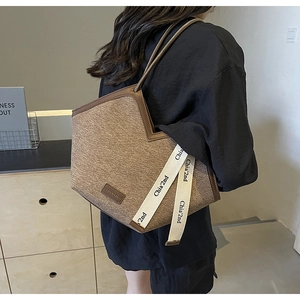 Détail d'un grand sac fourre-tout en tissu minimaliste avec lanières en cuir sur modèle