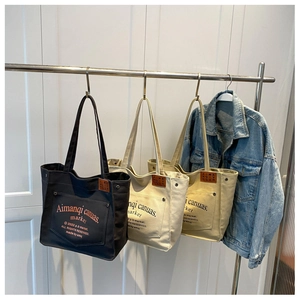 Detailed texture of large canvas tote bags in black, beige, and khaki with front pocket