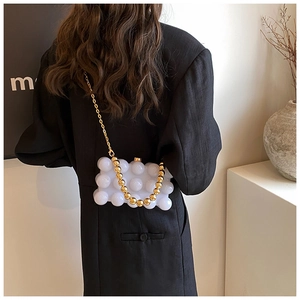 Detail of white bubble texture crossbody bag with gold bead chain strap and clasp