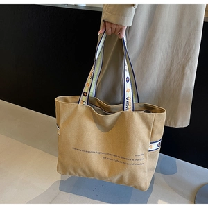 Detail of khaki canvas tote bag featuring contrast straps and printed text design
