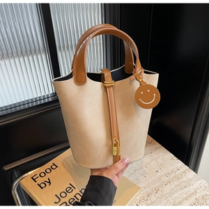 Detail of canvas bucket bag with brown leather handles and golden padlock closure