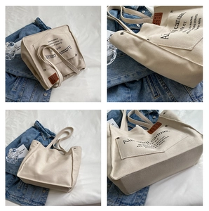 Detail view of large canvas tote bag with artistic text print and brown leather tag