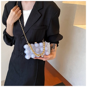 Detail of lavender bubble textured handbag with gold spherical clasp and chain strap