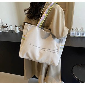 Detail of canvas tote bag with colorful logo straps and slogan print shown on model