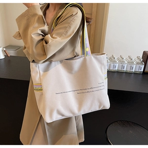 Detail of beige canvas tote with philosophy text and purple-yellow shoulder strap