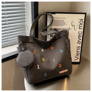 Detail of dark grey canvas tote with colored letter embroidery and small round pouch
