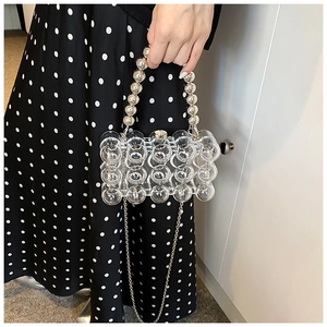 Detail of transparent bubble acrylic handbag with silver beaded handle and metal chain strap