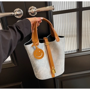 Detail of light blue denim bucket bag with brown leather handles and gold padlock charm
