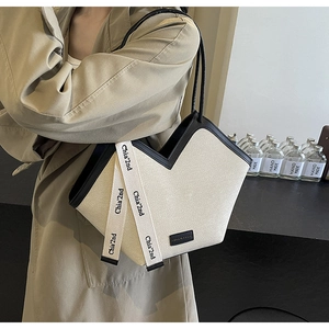 Détail du sac cabas en toile crème avec finitions en cuir noir et design unique en V