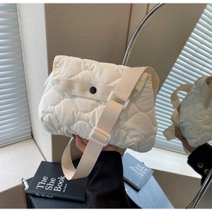 Detail of white quilted puffy shoulder bag with wide strap and snap closure design