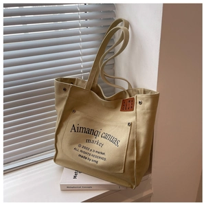 Detail of khaki canvas tote bag with metal rivet pockets and stylish letter printing