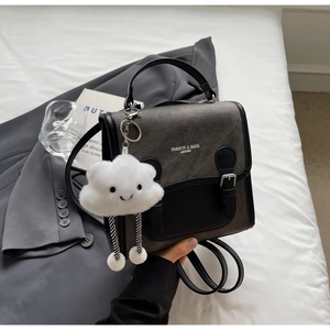 Vista detallada de mini mochila gris con correas de hebilla y colgante de nube suave