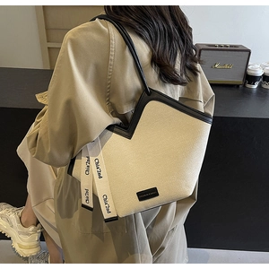 Détail du sac cabas tissé beige avec ouverture en V et poignées en cuir noir