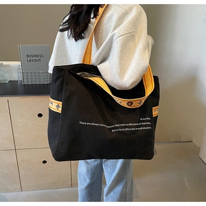 Detail of black canvas tote bag with contrast yellow floral pattern shoulder strap