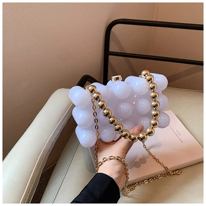 Detail of white bubble cloud clutch bag with gold beaded handle and metal chain strap